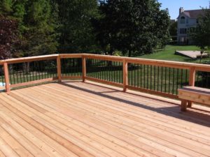 Wood deck with rail system overlooking green grass in expansive backyard